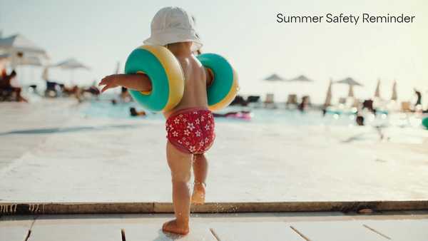 Child wearing a sun hat and colorful arm floaties walks toward a swimming pool on a sunny day. Text in upper right reads, “Summer Safety Reminder.”